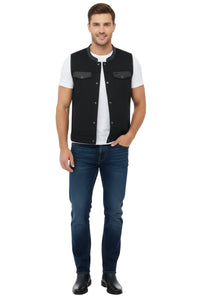 Man wearing a black vest over a white shirt with blue jeans on a white background