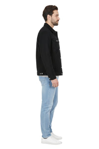 Man wearing a black jacket and light blue jeans on a white background