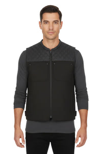 Man wearing a black quilted vest over a gray long-sleeve shirt on a white background