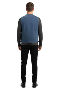 Man wearing a blue vest over a black long-sleeve shirt with black pants on a white background