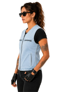 A woman wearing a light blue denim motorcycle vest over a black t-shirt, black pants, black fingerless gloves, and sunglasses, shown in profile against a white background.