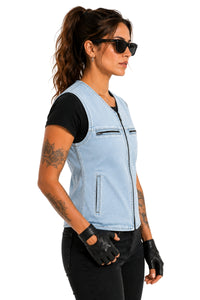 A woman wearing a light blue denim motorcycle vest over a black t-shirt, black pants, and black fingerless gloves, shown in profile against a white background.
