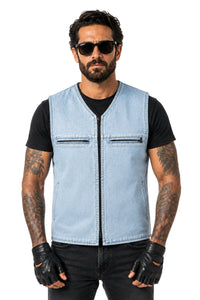 A man modeling a light blue denim motorcycle vest over a black t-shirt, black jeans, black fingerless gloves, and black sunglasses, against a plain white background.