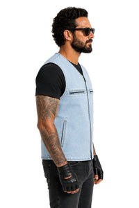 A man wearing a light blue denim motorcycle vest over a black t-shirt, black pants, and black fingerless gloves, shown in profile against a white background.