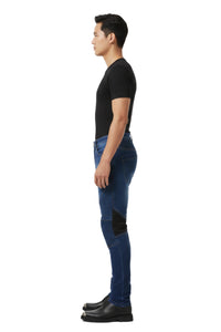Person wearing blue jeans with black patches on a white background