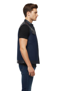 Man wearing a navy vest over a black shirt on a white background