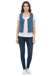 Woman wearing a blue denim vest over a white shirt with dark jeans on a white background
