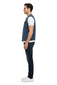 Man wearing a denim vest, white t-shirt, and dark jeans on a white background