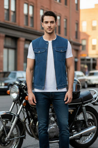Man standing next to a motorcycle wearing a denim vest and white shirt in an urban setting.