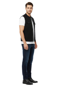 Man wearing a black vest over a white shirt with blue jeans on a white background