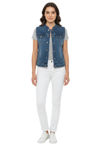 Woman wearing a denim vest over a gray shirt with white pants on a white background