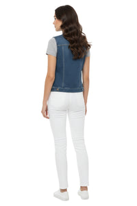 Woman wearing a blue denim pinafore over a gray top and white pants on a white background