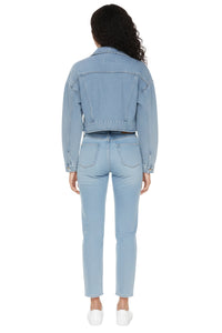 Person wearing a light blue denim jacket and jeans on a white background