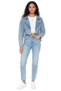 Woman wearing a light blue denim jacket and jeans on a white background