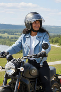 Woman on a motorcycle wearing a helmet with a scenic background