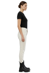 Woman wearing a black t-shirt, white pants, and black boots on a white background