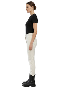 Woman wearing a black top, white pants, and black boots on a white background