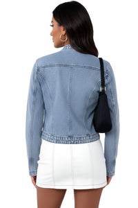 Woman wearing a light blue denim jacket and white skirt, carrying a black bag on a white background